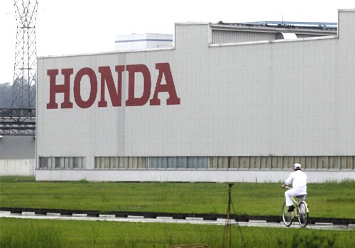 10804_a_worker_rides_a_bicycle_past_a_honda_auto_parts_manufacturi.jpg